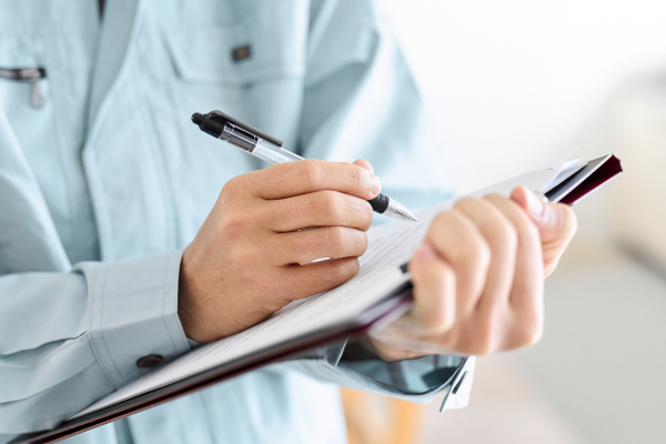 現地調査で点検内容をクリップボードに記入するスタッフ。